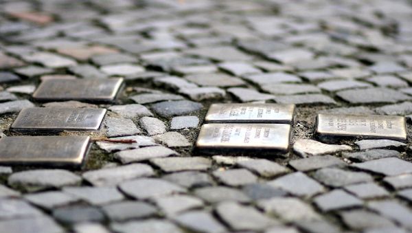 Abgeordnete reinigen Stolpersteine vor dem Hamburger Rathaus