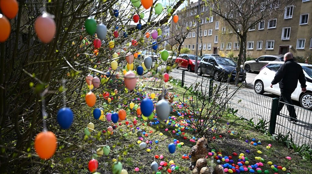 Eine Berliner-Straße mit tausenden bunten Ostereiern an Bäumchen und Wiesen