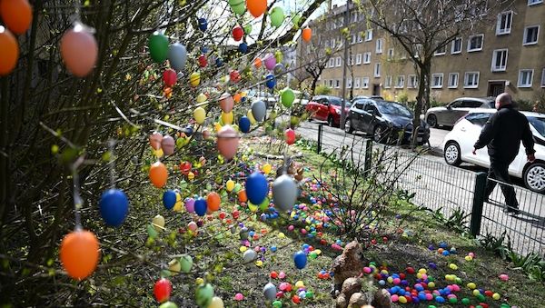 Eine Berliner-Straße mit tausenden bunten Ostereiern an Bäumchen und Wiesen